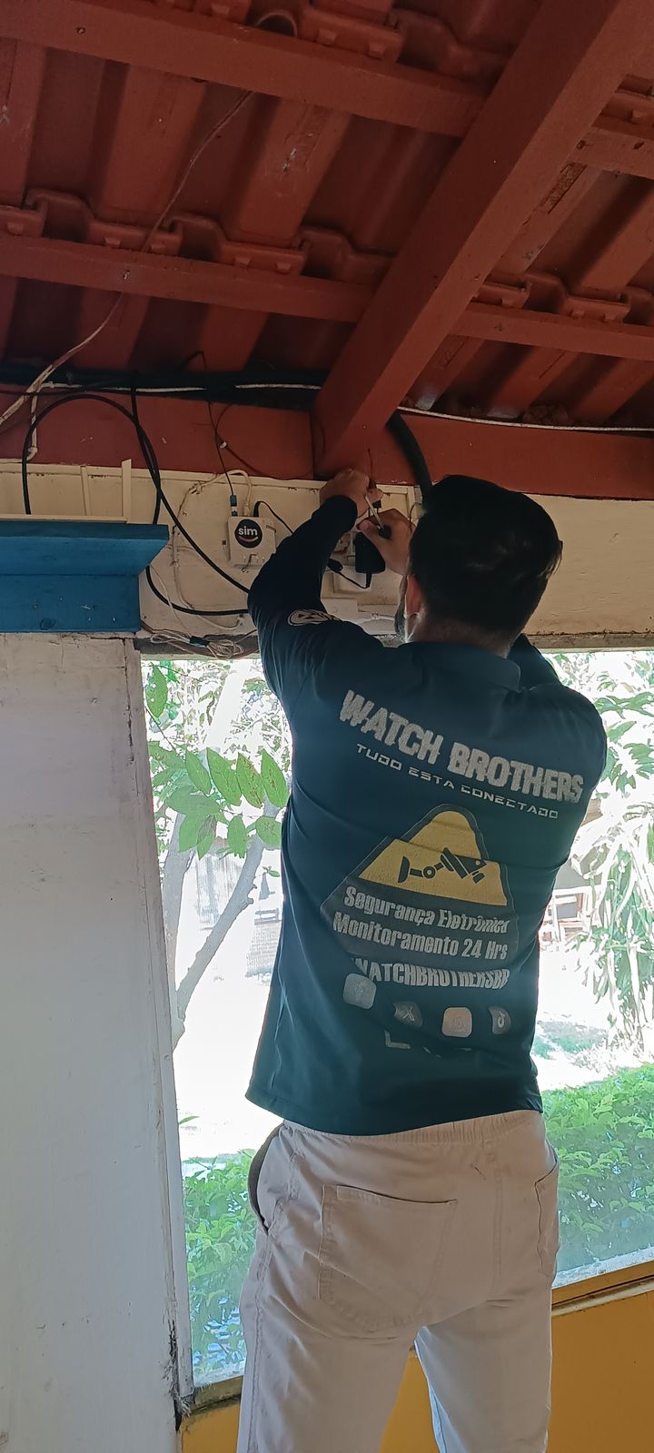 Técnico da Watch Brothers fixando equipamento de rede na estrutura do telhado