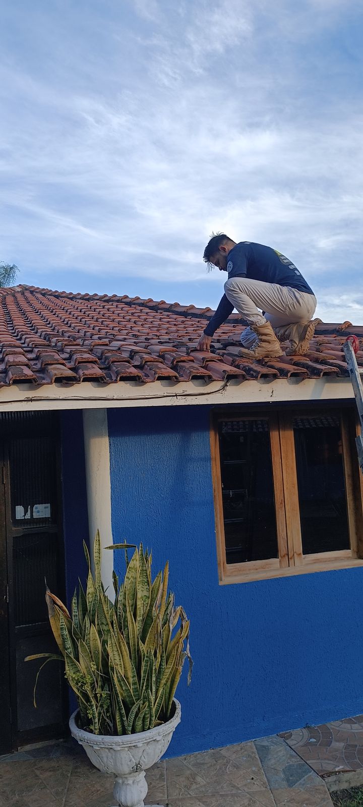 Técnico da Watch Brothers instalando câmera de CFTV no telhado de uma residência
